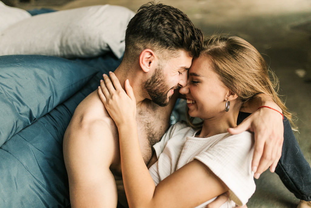 Mann und Frau nah aneinander liegend und lachend