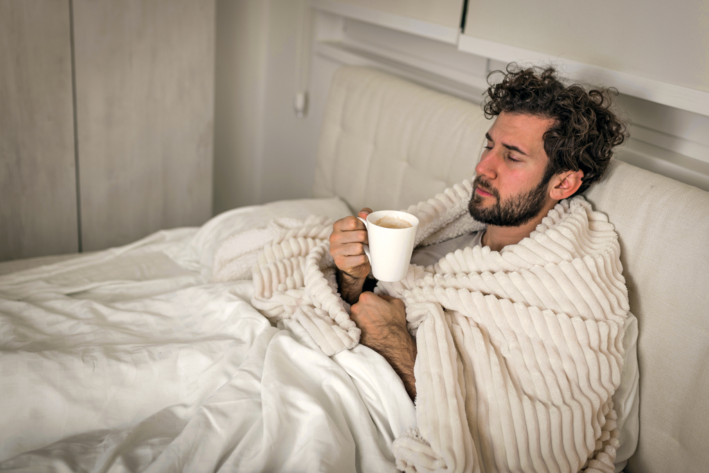 Mann liegt krank im Bett