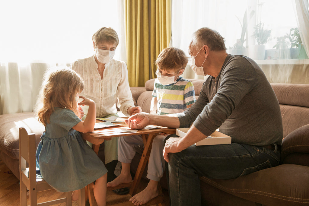 Großeltern sitzen während der Coronapandemie mit ihren Enkeln am Tisch und spielen