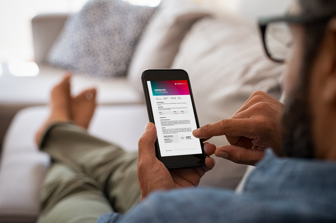 Mann von hinten auf dem Sofa liegend mit dem Handy in der Hand